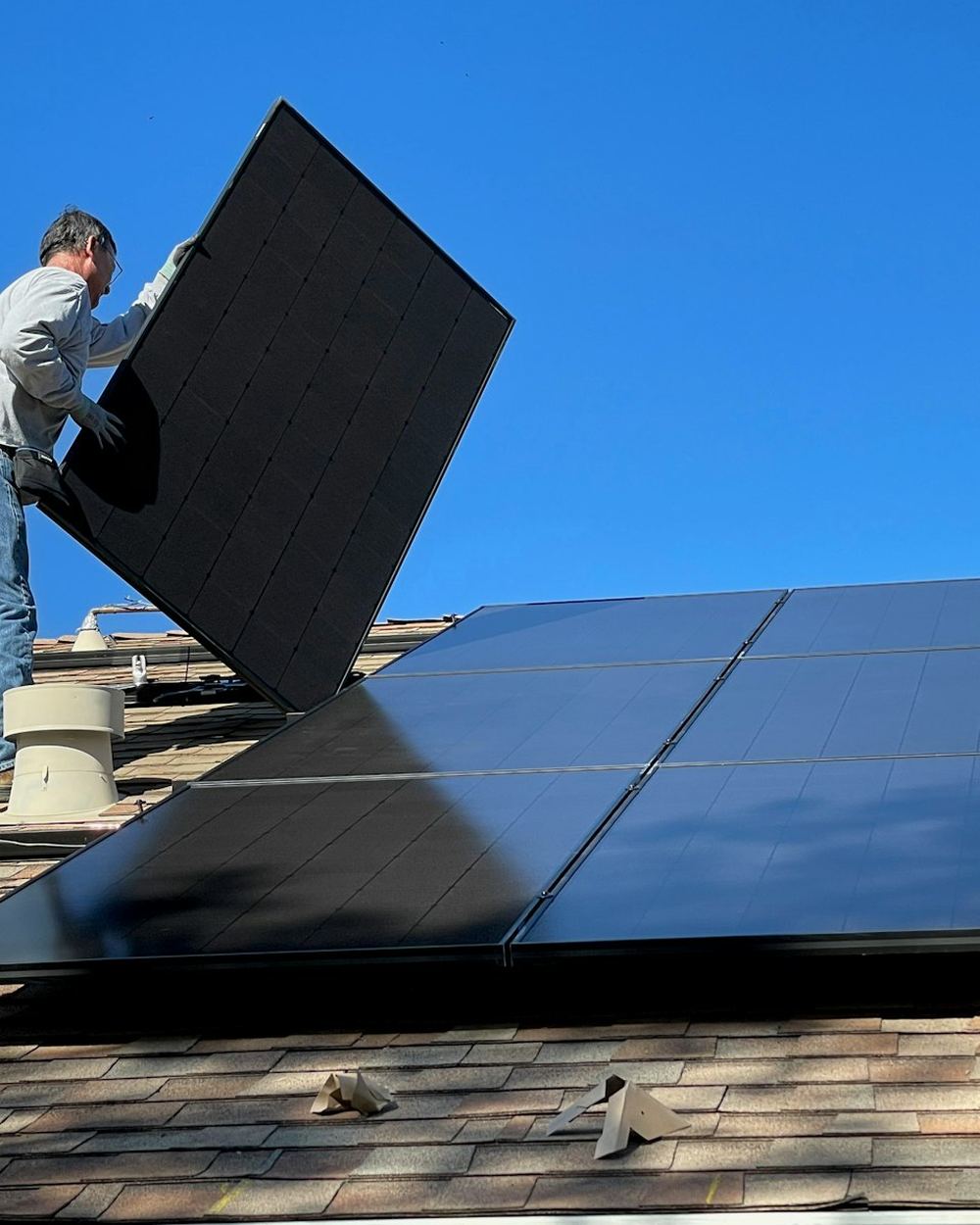 An installer placing a solar panel on a roof