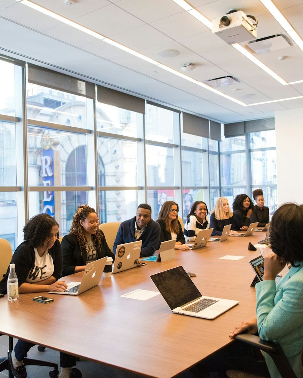 A team meeting around a long table with laptops